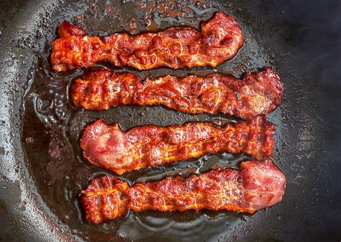 Bacon slice being cooked in frying pan. Close up.
