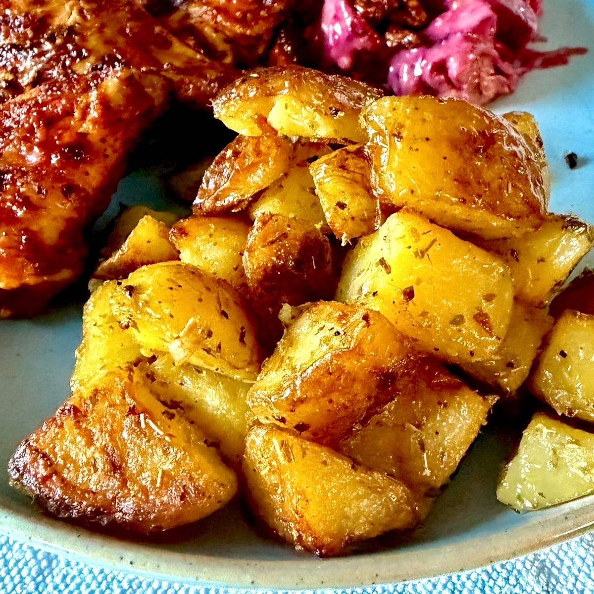 Lemon Oregano Oven Potatoes close up photo on a blue plate for Google featured image.