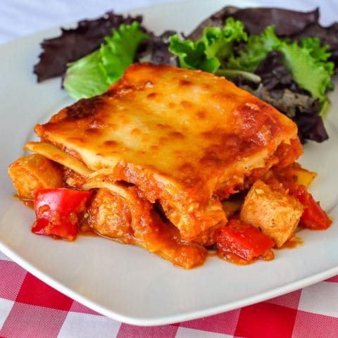 Chicken Parmesan Lasagna photo of single serving with salad on a white plate.