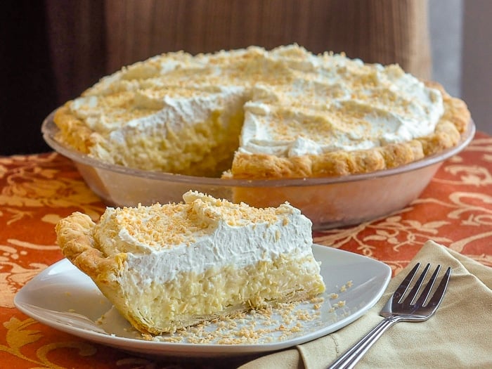 Coconut Cream Pie wide shot of slice of pie with full pie in background