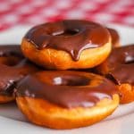 Chocolate glazed homemade donuts on white serving plate