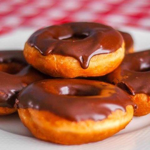 Chocolate glazed homemade donuts on white serving plate