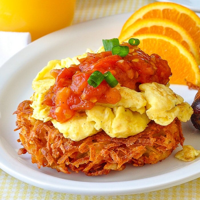 Garlic Parmesan Potato Latkes close up photo of one latke topped with scrambled egg and tomato compote