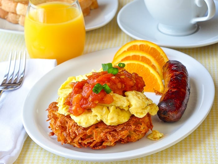 Garlic Parmesan Potato Latkes shown with scrambled eggs, tomato compote and sausage