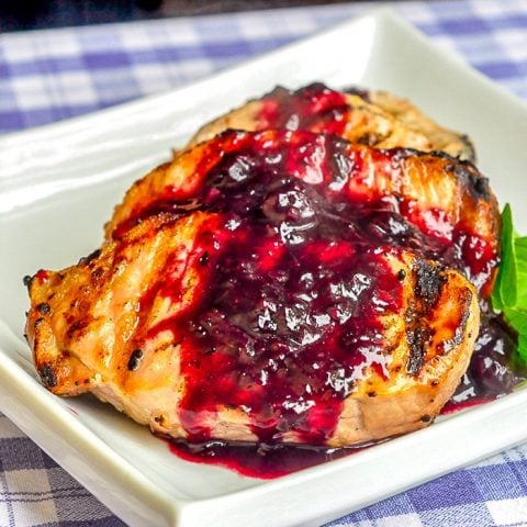 Blueberry Balsamic Pork Chops on a white serving platter with herb garnish