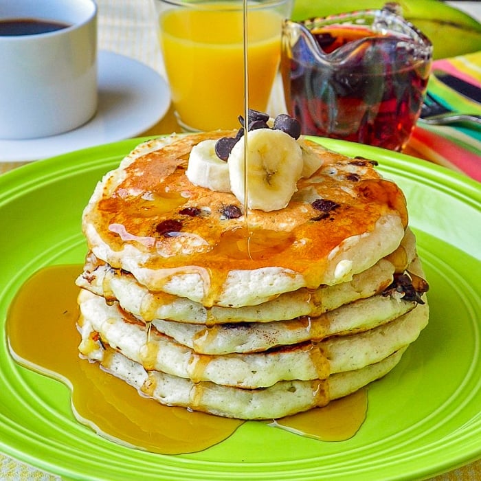 Chocolate Coconut Banana Pancakes close up with maple syrup being poured on