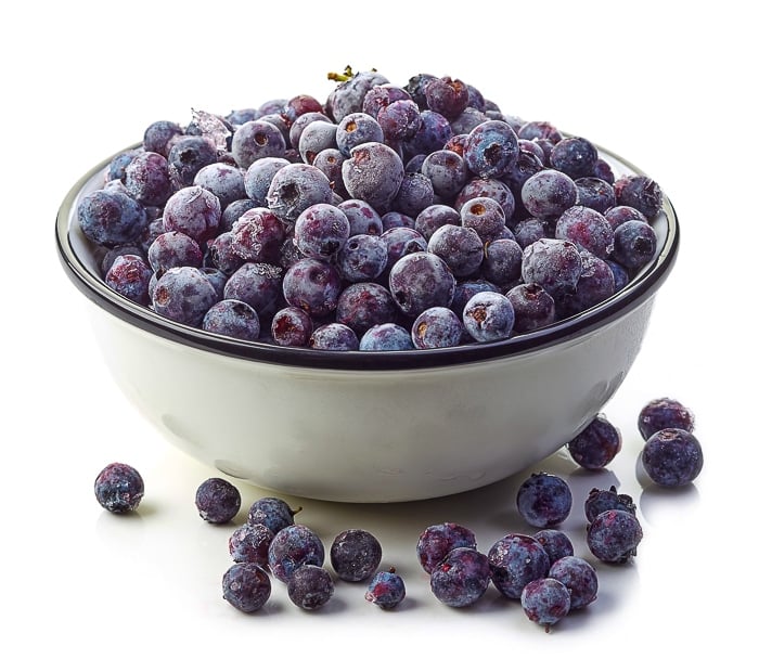 stock photo of frozen blueberries in a white bowl.
