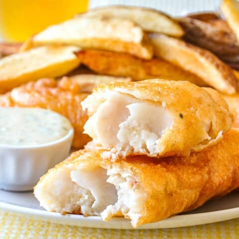 Super Crispy fish and chips close up photo of one piece of cooked fish broken open to reveal interior