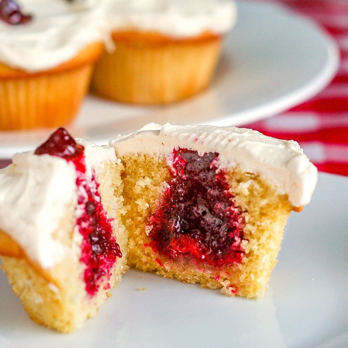 Vanilla Buttercream Cupcakes close up photo of one cupcake revealing the jam centre