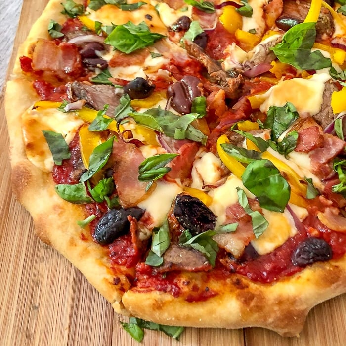 Barbecue Steak Pizza close up photo of cut pizza on a wooden cutting board