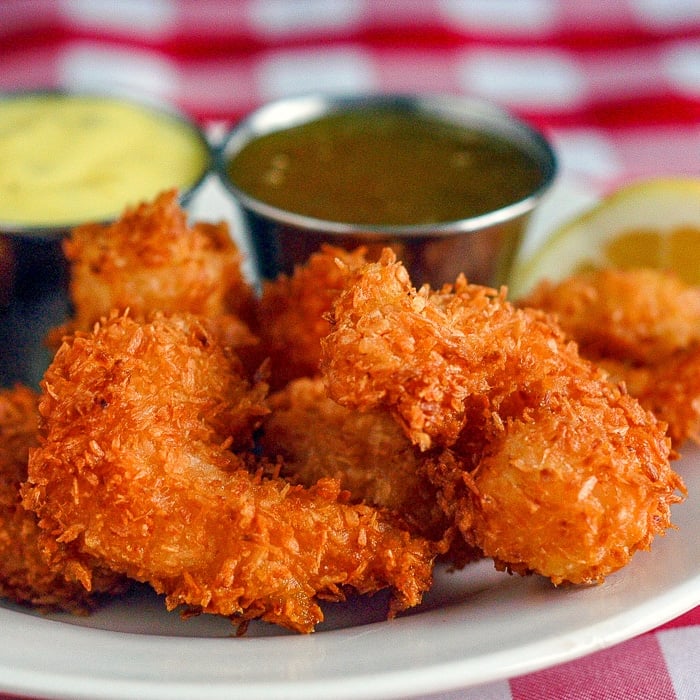 Coconut shrimp close up of 2 shrimp with dipping sauce in the background.