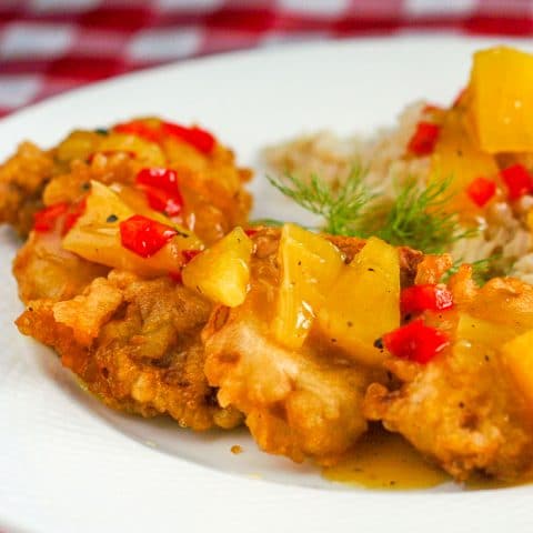 Tempura Pork Tenderloin Medallions with Pineapple Ginger Sauce shown served with rice on a white plate.