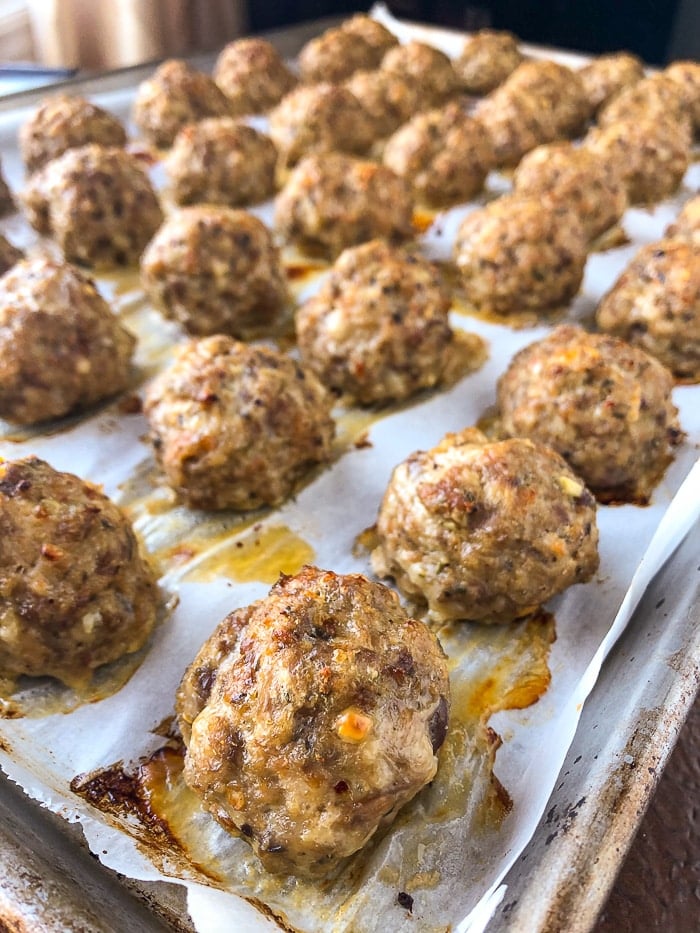 Italian Sausage Meatballs fully cooked on a parchment paper lined baking sheet.