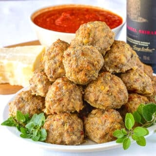 Italian Sausage Meatballs stacked on a white plate garnished with oregano.