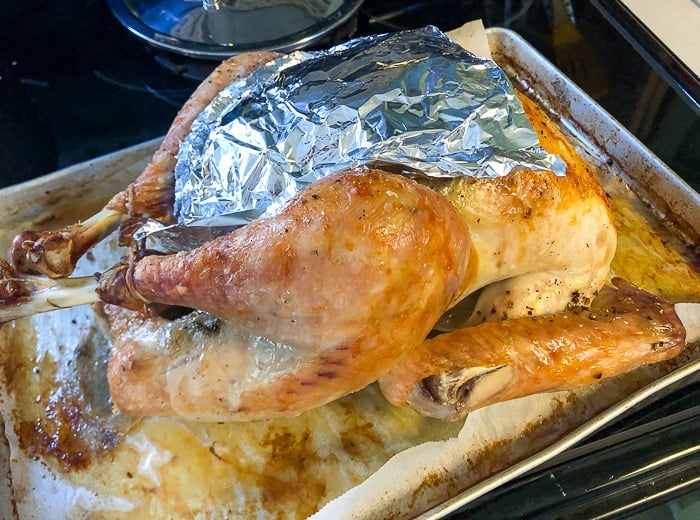 Photo showing a sheet of aluminum foil over the breast of the turkey