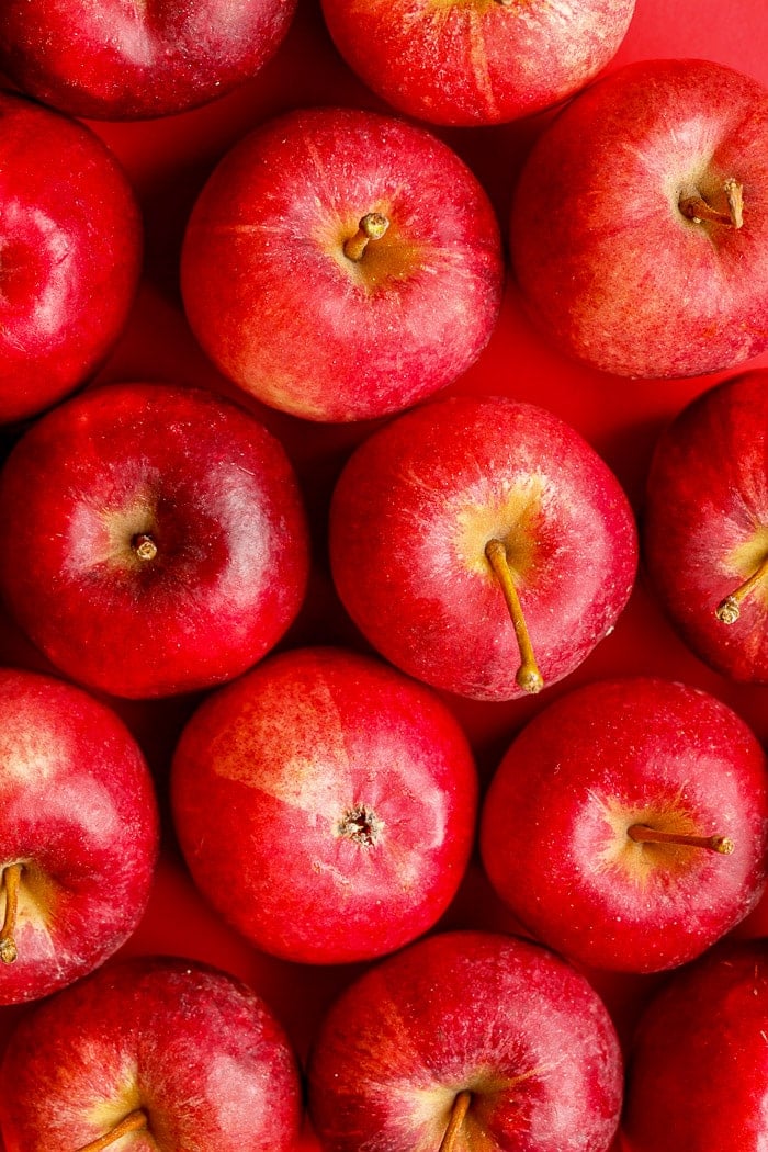 Red delicious apples on a red background. Stock photo.