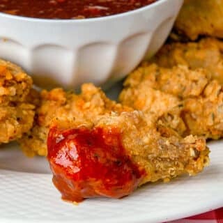 Fried Chicken Wings with Blackstrap Barbecue Sauce. Photo shows one dipped wing, close up.