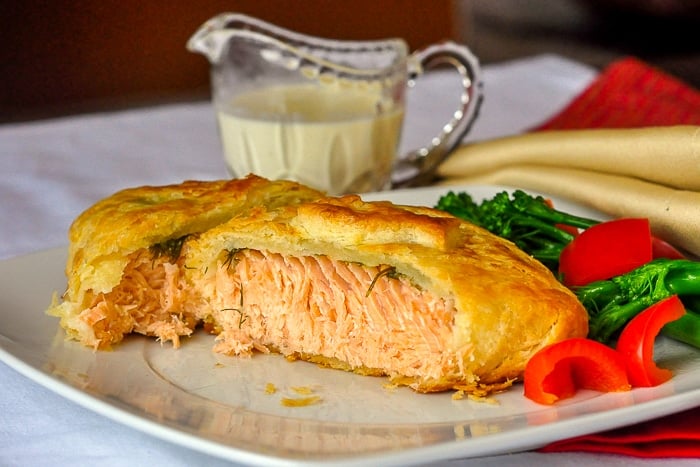 Salmon in pastry wide shot photo with vegetables on a white plate