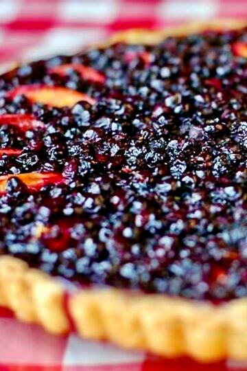 Blueberry Nectarine Tart. Photo of an uncut tart on a red & white checkered background