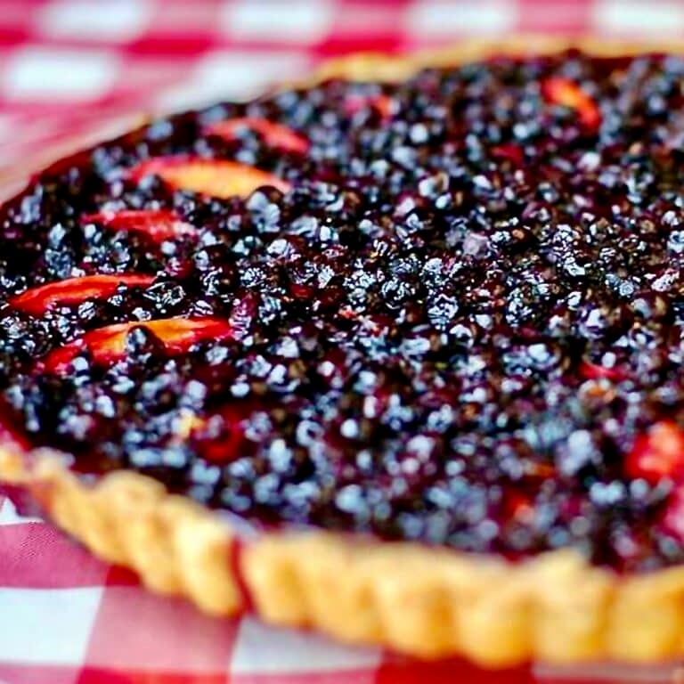 Blueberry Nectarine Tart. Photo of an uncut tart on a red & white checkered background