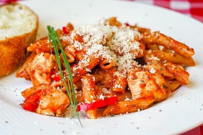 Roasted Fennel Marinara Chicken Penne photo of one serving on a white plate with a slice of sourdough bread.