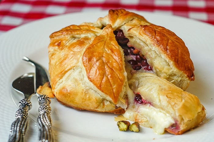 Wide shot of baked brie being served on a white platter