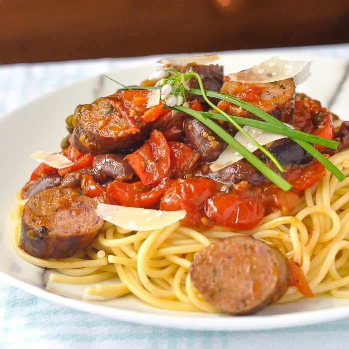 Italian Sausage Pasta Puttanesca closer up photo of a single serving on a white plate