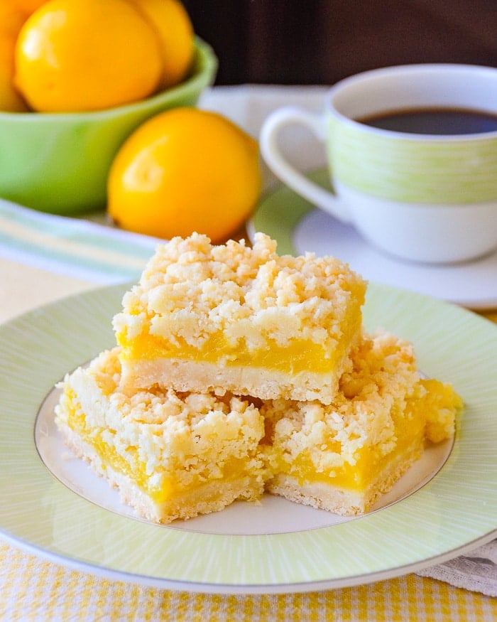 Coconut Lemon Crumble Bars shown with coffee and fresh bowl of lemons.