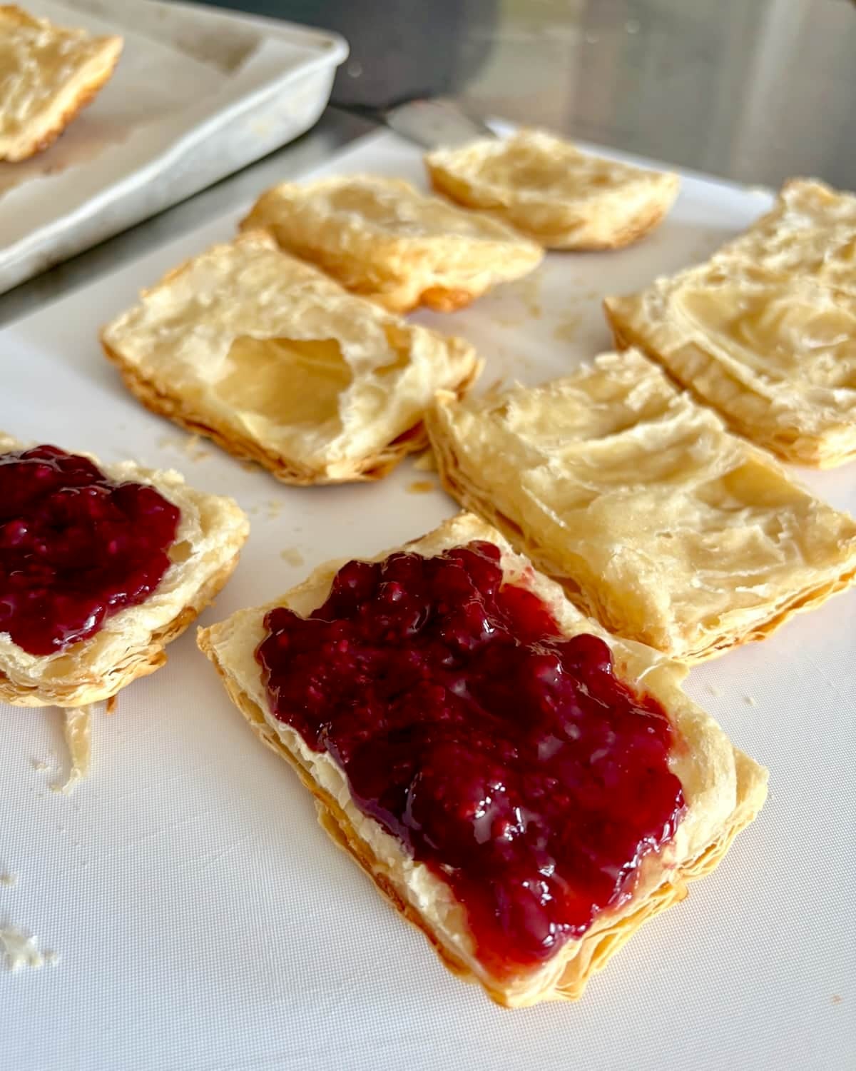 Ice Cream Sandwich Flakies photo of raspberry jam being spread in the bottom half of the pastries.