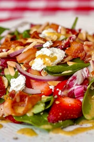 Strawberry Spinach Salad close up photo of finished salad on a white plate
