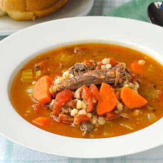 Beef Barley Soup with Tomatoes close up photo pf soup in a white bowl.