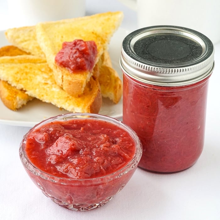 Heavenly Rhubarb Jam in a small serving dish with full mason jar on the side
