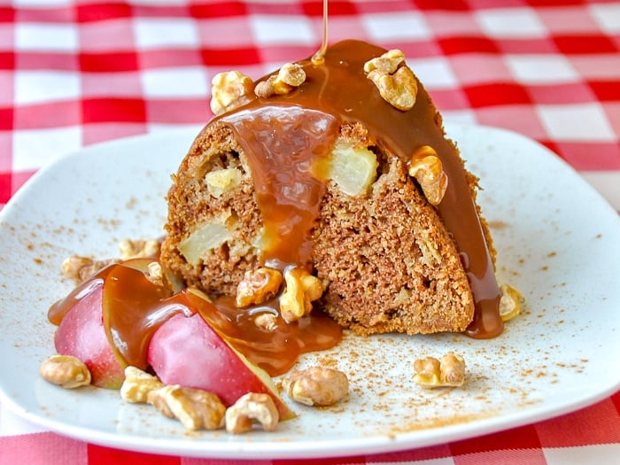 Warm Apple Cake with Caramel Sauce and Toasted Walnuts single serving on a white plate on red checkered tablecloth