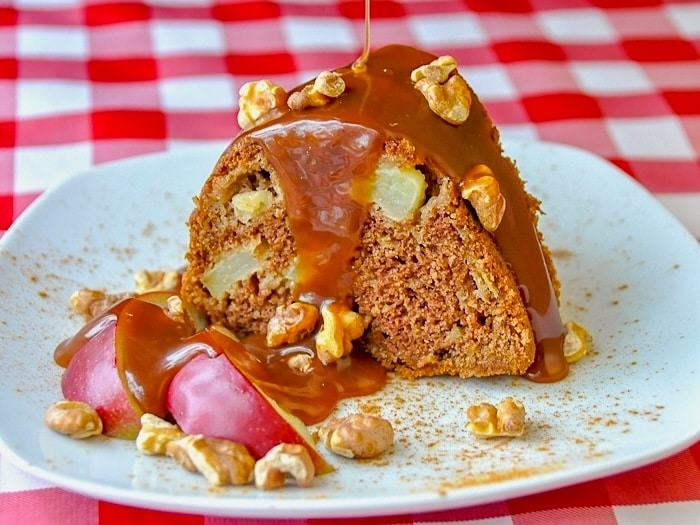 Warm Apple Cake with Caramel Sauce and Toasted Walnuts with a red checkered tablecloth background