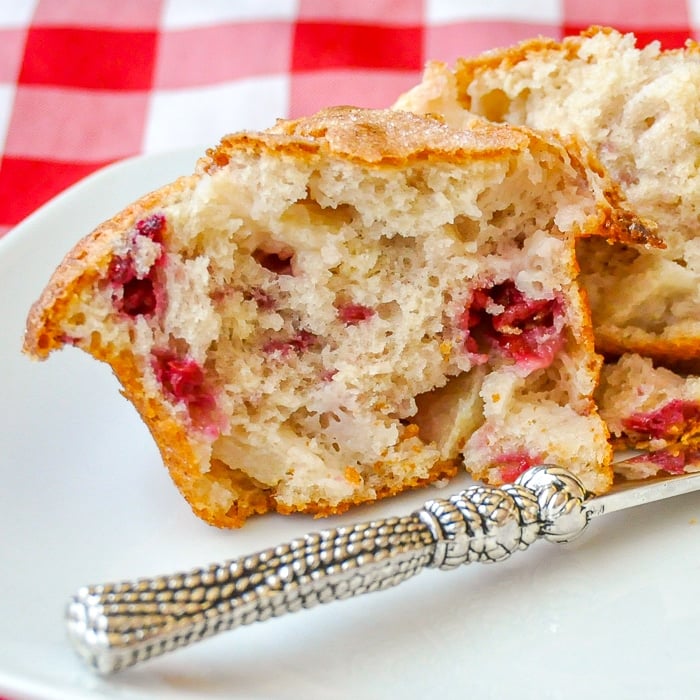 Apple Raspberry Muffins close up photo of one muffin split open on a white plate with butter knife