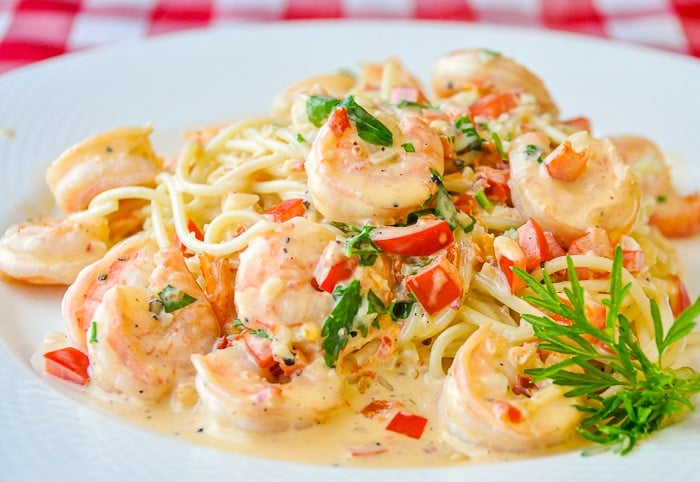 Spicy Creamy Garlic Shrimp Pasta on a white plate with herb garnish