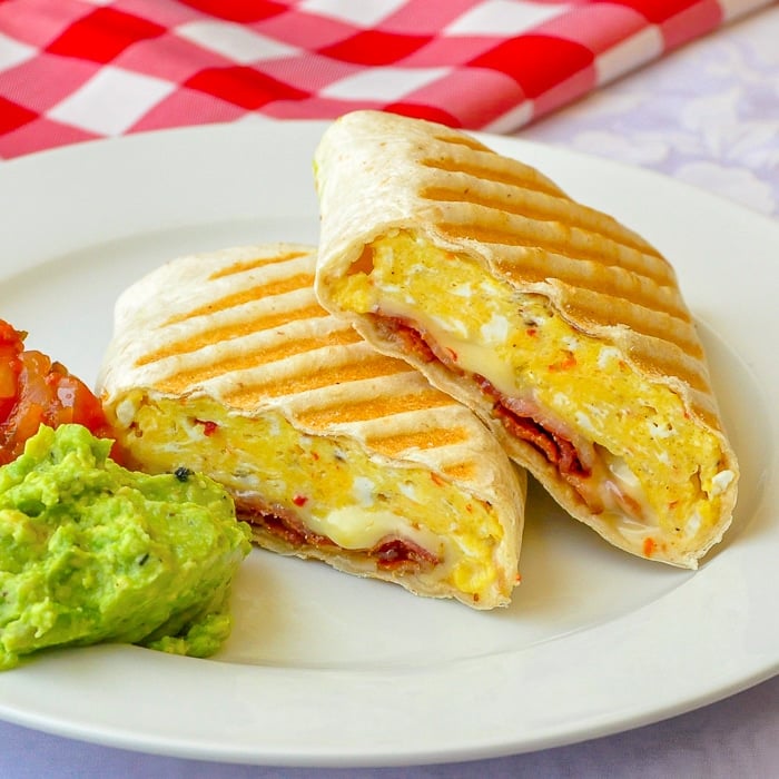 Bacon Jack Breakfast Burritos photo of one burrito on white plate with guacamole and salsa.