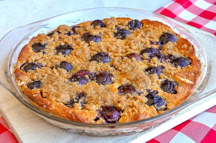 Cherry Almond Clafoutis fresh from the oven cooling on a wooden cutting board