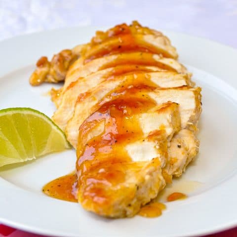 Glazed Lime Apricot Chicken Breasts on a white plate with lime garnish
