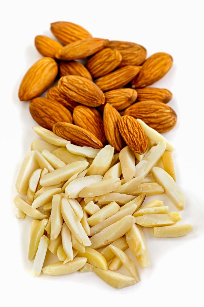 Whole and slivered raw almonds in a pile on white background for Cherry Almond Clafoutis