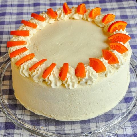 Orange Creamsicle Cake photo of entire completed cake on a clear glass cake plate