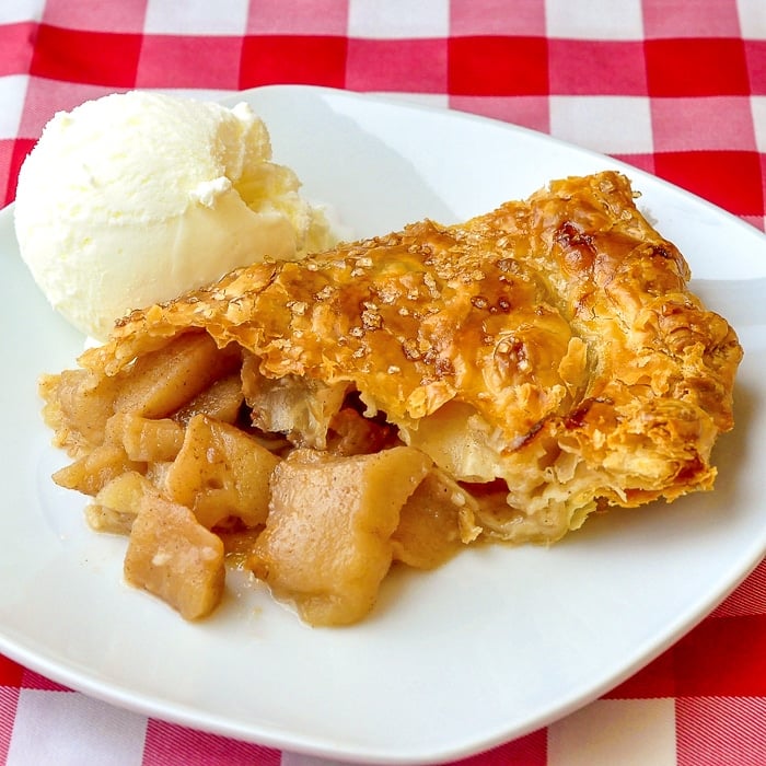 Apple Turnover Pie photo of a single slice on a white plate with a scoop of ice cream