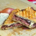 Blue Cheese Steak and Red Onion Jam Panini shown cut in half to reveal filling