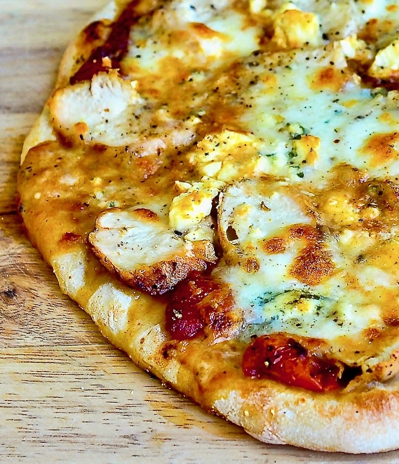 Buffalo Wing Pizza close up photo on a wooden cutting board wider shot photo