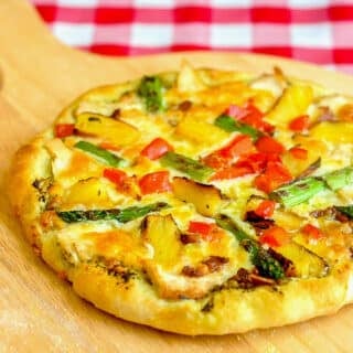 Pineapple Pizza with Grilled Chicken and Asparagus shown on a wooden peel
