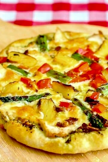 Pineapple Pizza with Grilled Chicken and Asparagus shown on a wooden peel
