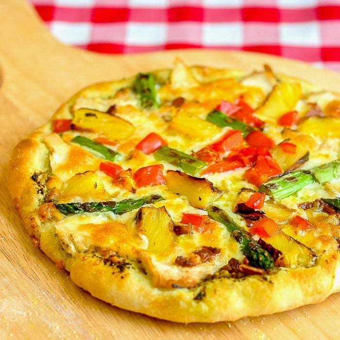 Pineapple Pizza with Grilled Chicken and Asparagus shown on a wooden peel