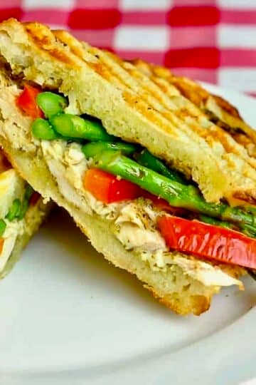 Photo of Asparagus Panini with pesto and grilled chicken shown on a white plate.