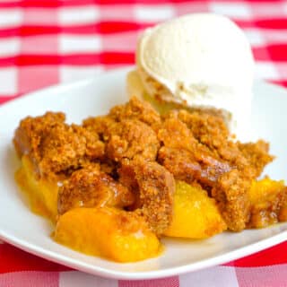 Ginger Snap Peach Crumble photo of a singoe serving on a white plate with vanilla ice cream