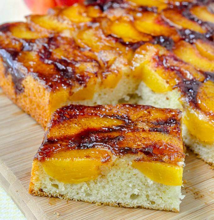 Peach Upside Down Cake close up photo of a single sice on a wooden cutting board.